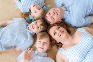 vista superior lindos niños y sus hermosos padres jóvenes mirando a la cámara foto