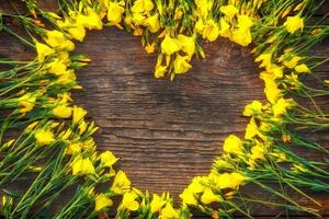 corazón de flores amarillas sobre fondo de madera, concepto de amor y romance, espacio de copia foto