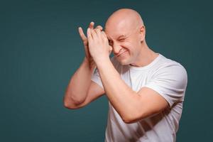 a man on a blue background in holding hands near his eyes like a telescope Peeps photo