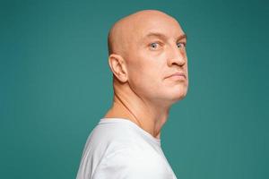 portrait of a bald man in a white t-shirt on the background, facial expression photo
