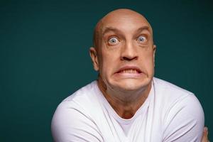 bald man with facial expressions on a blue background photo