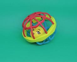 colorful baby rattles or teethers isolated on green background photo