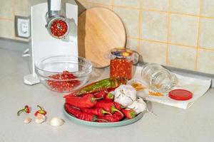 cooking adjika from hot pepper and garlic ground in a meat grinder. preparations for the winter. folk remedy for flu and colds photo