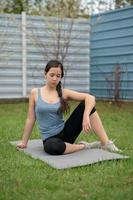 Fitness. Girl sitting on the lawn in the yard of her house, doing excise. photo