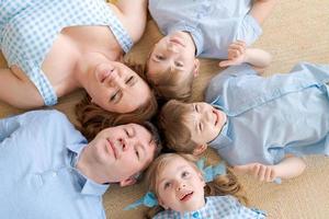 retrato feliz familia caucásica posando en el piso de la casa, acostado en la alfombra foto