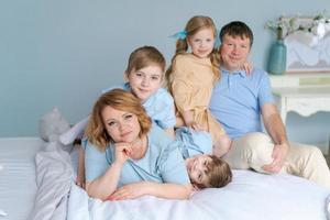 familia alegre jugando juntos en la cama. los padres pasan su tiempo libre foto