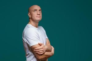 Portrait of a bald adult man with a sad expression in a white t shirt on a blue background photo