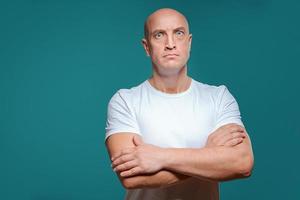 beautiful bald serious man in white t-shirt on blue background photo