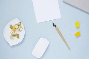 Workplace of a blogger, artist, or calligrapher. A sheet of white paper, a fountain pen, a mouse, a notebook, a glider or a diary and watercolour paints in ditches photo