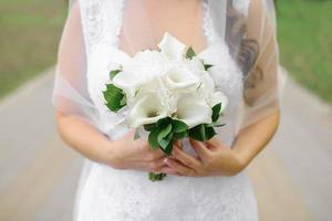 Bridal bouquet of white calla lilies in the hands of the bride close-up photo