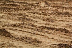 Tire track mark lines shape on dry sand background. Trail tyre imprint from heavy machinery. Vehicle shape. Road construction site backdrop concept. Trace of wheel pattern on mud. Nature texture. photo