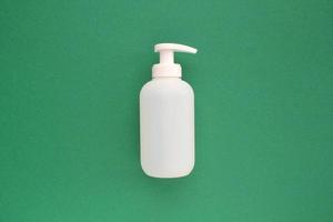 White unbranded plastic dispenser pump bottle on green background with copy space for text. Cosmetic package mockup, liquid soap flacon, hand sanitizer without label, shampoo organic spa, shower gel photo