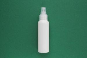 White unbranded plastic dispenser spray bottle on green background with copy space for text. Cosmetic package mockup, liquid soap flacon, hand sanitizer without label, shampoo organic spa, shower gel photo