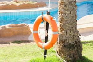 orange emergency lifebuoy hanging on fence near pool on vacation at the hotel photo