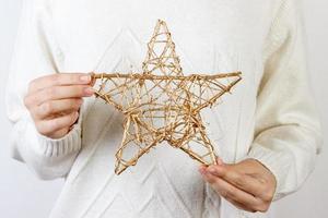 Hands of young woman holding a golden star for Christmas decoration photo