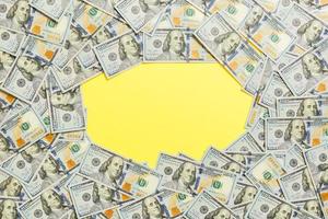 Frame of one hundred dollar bills with empty space for your design. Top view of business concept on yellow background with copy space photo