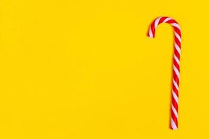 one christmas candy cane on yellow backgroud, copy space photo