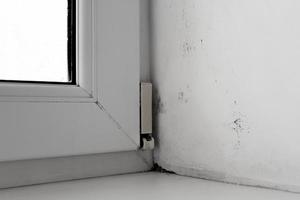 mold in the corner of the window on a white wall Texture background photo