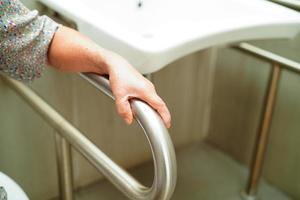 Asian elderly old woman patient use toilet support rail in bathroom, handrail safety grab bar, security in nursing hospital. photo