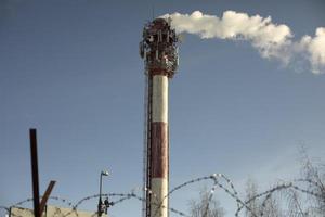 Chimney with smoke. Boiler station. Industrial pipe on sky. photo