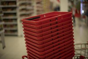 Red baskets for products. Grocery basket in store. Supermarket details. photo