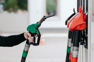 Car fueling concept. Mans hand using fuel nozzle at petrol station. Refueling pistols close up. Diesel and gas. Modern service photo