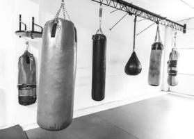 gimnasio de boxeo con bolsas colgantes, fotografía deportiva en blanco y negro foto