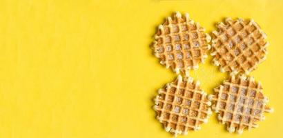 Top view, four sugar belgium waffles on yellow background, copyspace.Sweet dessert. photo