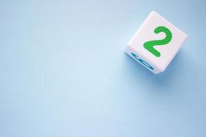 Close-up photo of a white plastic cube with a green number 2 on a blue background in the upper right corner. With copy space