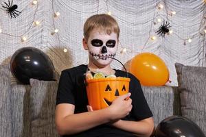 The child takes out the candy from the bucket for Halloween photo