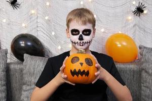 adolescente con maquillaje en la cara y con una calabaza en las manos para halloween. foto