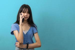 joven mujer de negocios asiática usando un teléfono inteligente con fondo azul. foto