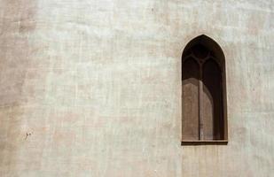 pared gris de hormigón con ventana árabe cubierta con malla fina oxidada foto