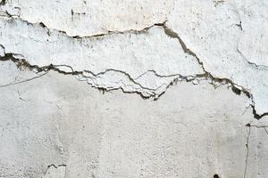 Concrete wall painted white with cracks on it photo