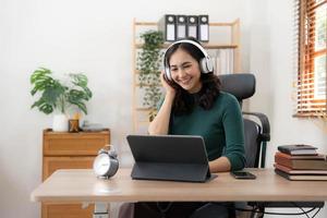 Young Asian woman wearing headphones to study online with her teacher, the girl is happy to learn. photo