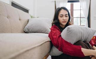 Unhappy asian pretty young woman siting alone on couch with feeling sadness photo