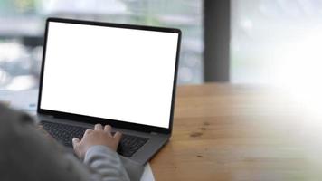 Mockup image of a woman using and typing on laptop with blank white desktop screen on wooden table photo