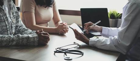 Doctor or physician writing diagnosis and giving a medical prescription to female Patient photo