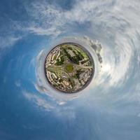 tiny planet in sky with clouds overlooking old town, urban development, historic buildings and crossroads. Transformation of spherical 360 panorama in abstract aerial view. photo