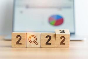 2023 block with magnifying glass icon against laptop background. Hiring, recruitment, job, jobless SEO, Search Engine Optimization and New Year concepts photo