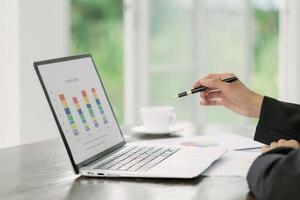 Financial analyst with document in his hands reading information on computer screen photo