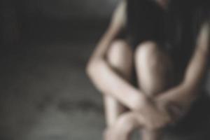 Blurred image of Young  women sitting in dark room feeling pain with life problem.   Stop violence against and sexual abuse women, domestic violence, human trafficking. photo