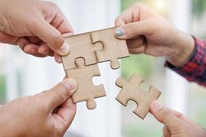 Group of business people assembling jigsaw puzzle and represent team support and help concept photo