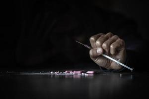 Human hand of a drug addict and a syringe with narcotic syringe lying on the floor. World Anti-drug Day. photo