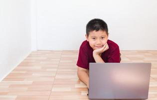 Asian boy studying online on computer laptop with smiling and happy face at home. online education and e-learning concept. photo