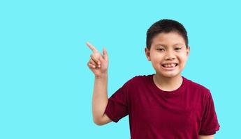 Smiling happy Asian boy pointing his finger away at copy space isolated over a plain white background photo