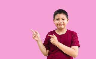 un niño asiático sonriente y feliz señalando con el dedo el espacio de copia aislado sobre un fondo completamente blanco foto