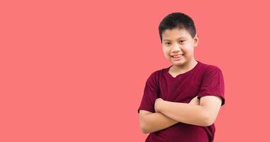 retrato de un niño asiático de pie sonriendo con los brazos cruzados gesto de confianza en un fondo blanco foto