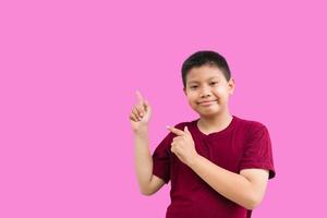 Smiling happy Asian boy pointing his finger away at copy space isolated over a plain white background photo