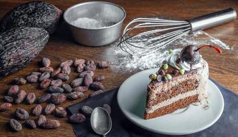 Slice of tasty homemade chocolate cake on the plate and Contain cocoa beans and starch as ingredients for cooking chocolate cakes on the table photo